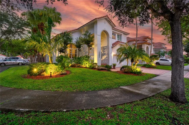 a front view of a house with garden and trees