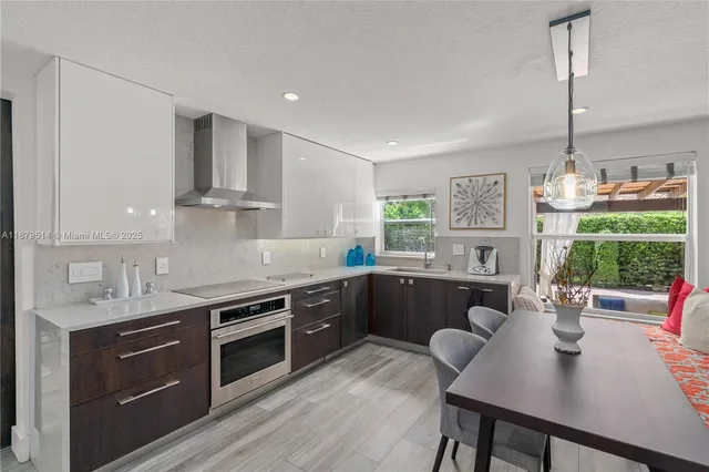 a kitchen with stainless steel appliances granite countertop a stove a sink a microwave a dining table and chairs with wooden floor