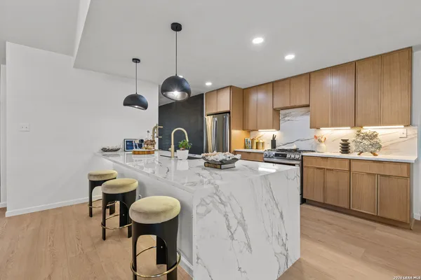 a kitchen with stainless steel appliances kitchen island granite countertop a stove a sink a dining table and chairs with wooden floor