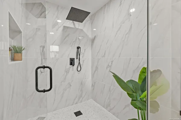 a bathroom with a granite countertop sink a mirror and shower