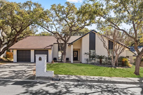 a front view of a house with a yard and large tree