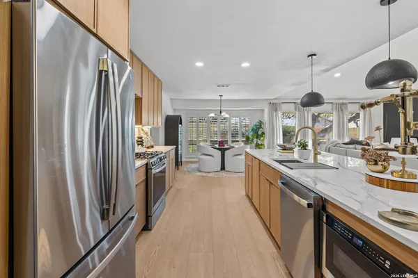 a kitchen with stainless steel appliances granite countertop a refrigerator a sink dishwasher a stove and a sink with wooden floor