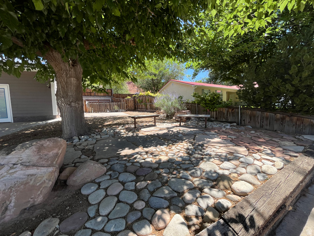 278 Hobbs Street Moab, UT 84532 - Photo 3 of 43 Outdoor patio featuring a stone and paver surface, bordered by a wooden retaining wall and a wood privacy fence