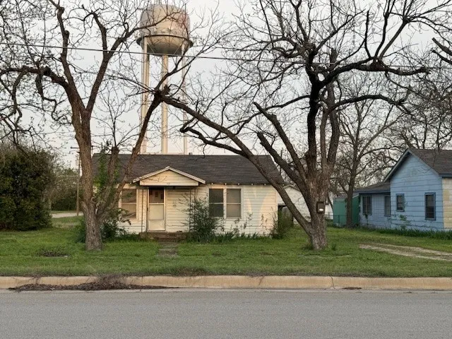 a front view of a house with a garden and trees