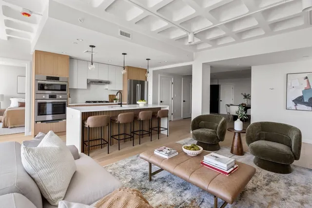 a living room with furniture a rug kitchen view and a window