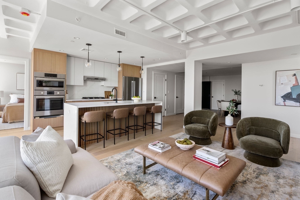 125 Lowell Street, Unit 402 Somerville, MA 02143 - Photo 5 of 34 a living room with furniture a rug kitchen view and a window