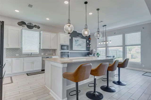 a large kitchen with stainless steel appliances a large center island attached withe living room