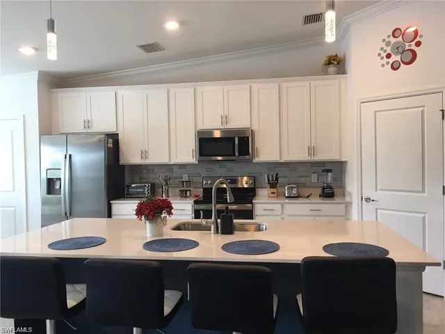 a kitchen with stainless steel appliances a sink a table and chairs