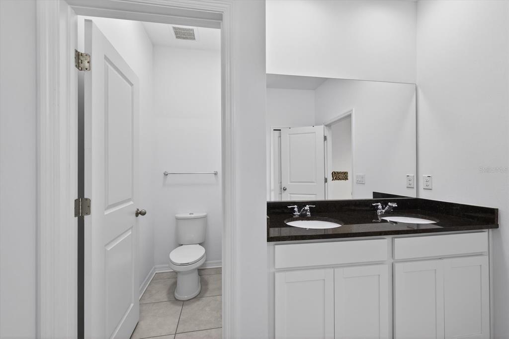 11883 Brighton Knoll Loop Riverview, FL 33579 - Photo 12 of 45 a bathroom with a granite countertop sink a toilet and a vanity