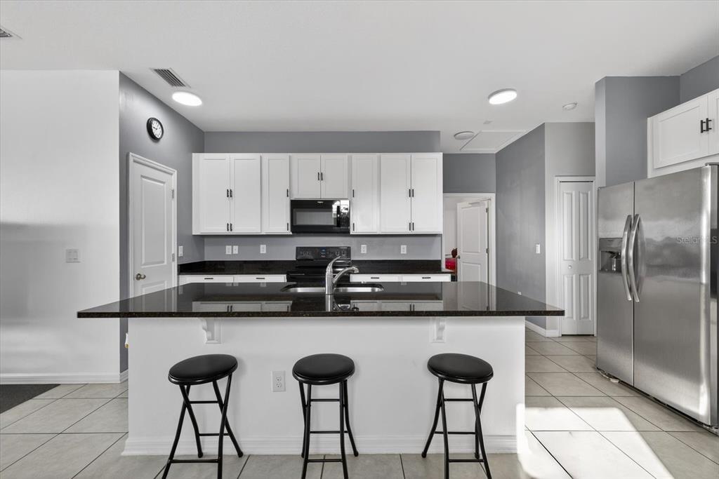 11883 Brighton Knoll Loop Riverview, FL 33579 - Photo 5 of 45 a kitchen with stainless steel appliances a stove a refrigerator and white cabinets with wooden floor