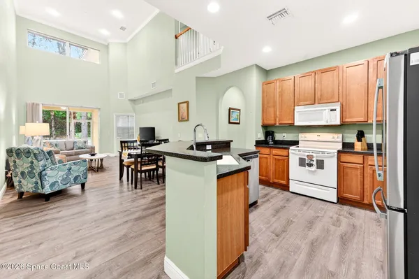 a kitchen with stainless steel appliances kitchen island granite countertop a stove a sink dishwasher and a dining table with wooden floor