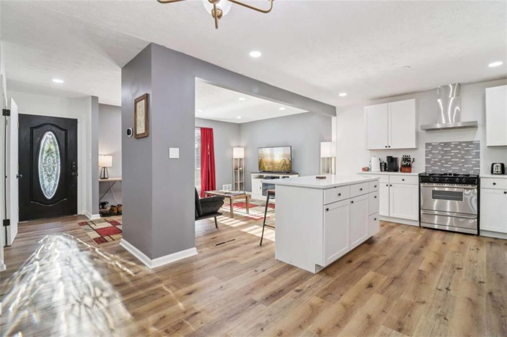 9202 Settlers Grove Road Northeast Covington, GA 30014 - Photo 12 of 45 a open kitchen with stainless steel appliances granite countertop a refrigerator a sink dishwasher and white cabinets with wooden floor