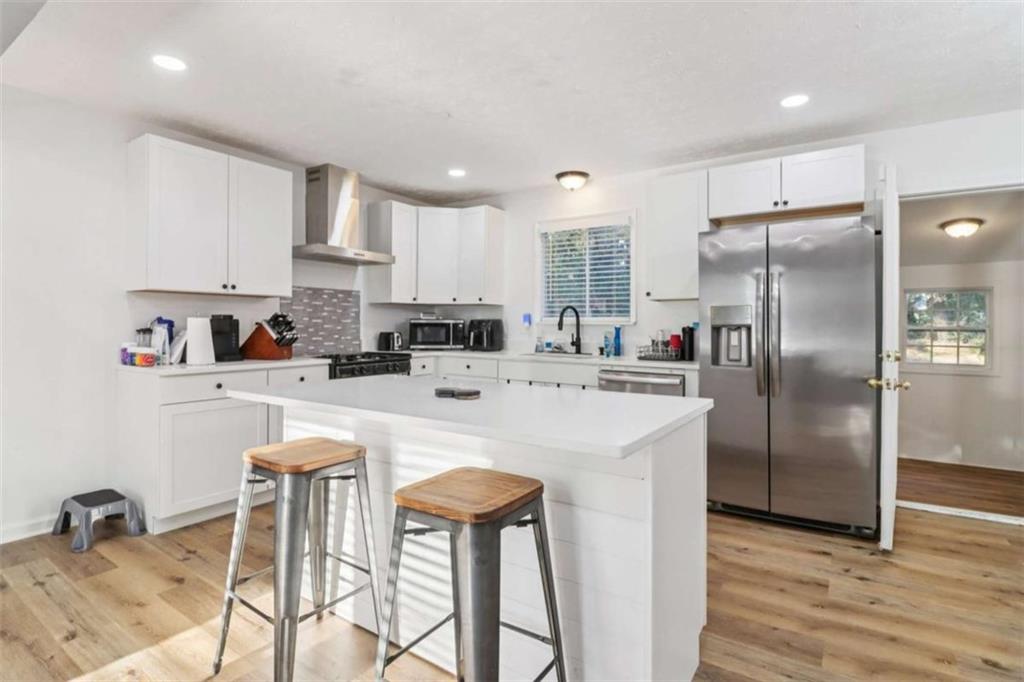 9202 Settlers Grove Road Northeast Covington, GA 30014 - Photo 14 of 45 a kitchen with stainless steel appliances granite countertop a refrigerator a stove a sink and white cabinets with wooden floor
