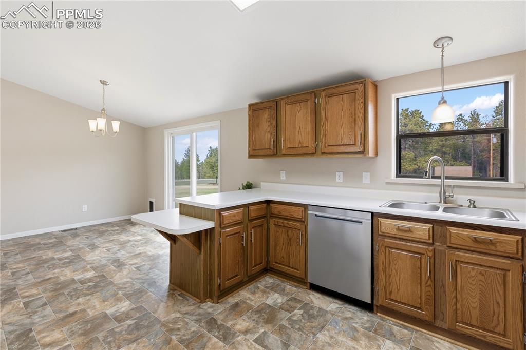 585 Mills Ranch Road Woodland Park, CO 80863 - Photo 27 of 46 Kitchen with stone finish flooring, light countertops, wood finish cabinetry, a peninsula, and lofted ceiling