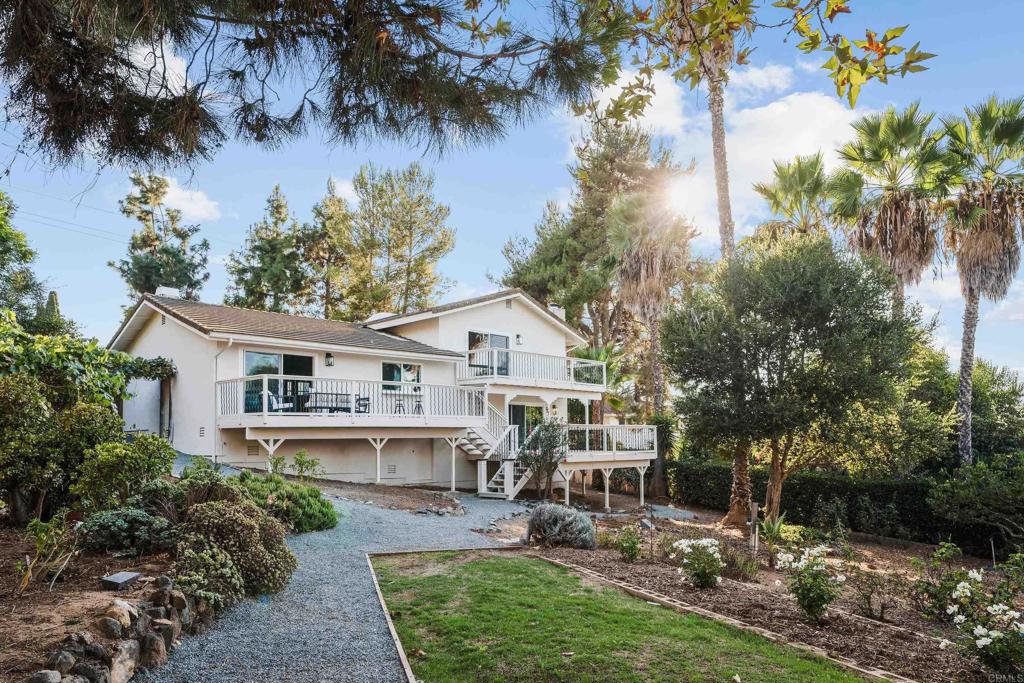 a view of a house with a yard potted plants and a large tree