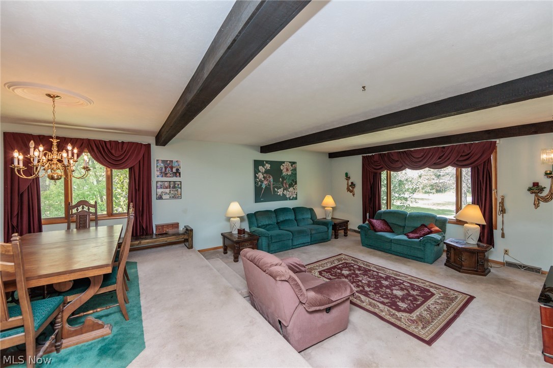 2170 Norton Road Stow, OH 44224 - Photo 22 of 48 Open-concept living and dining area featuring exposed ceiling beams, a brass chandelier with ceiling medallion, and large windows