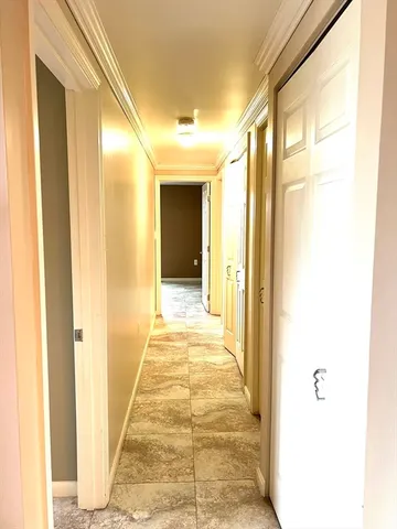 a view of a hallway with wooden floor and a bathroom