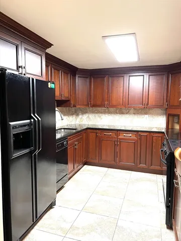 a kitchen with granite countertop a refrigerator and wooden cabinets