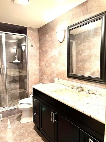 a bathroom with a granite countertop sink toilet and shower