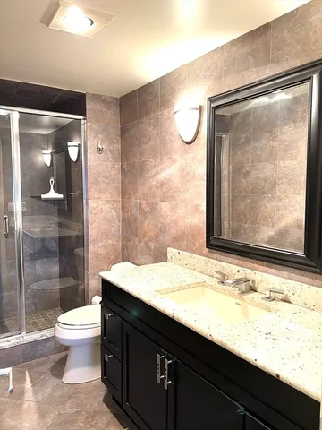 a bathroom with a granite countertop sink toilet and shower