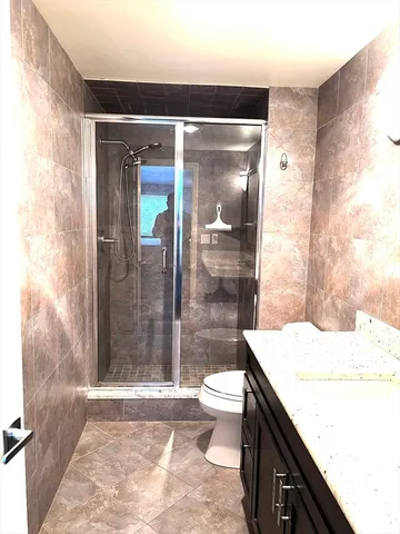 a bathroom with a granite countertop sink a toilet a mirror and shower