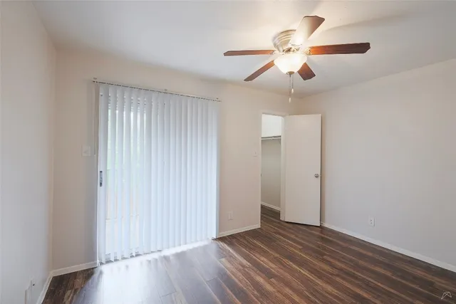 an empty room with wooden floor chandelier fan and closet area