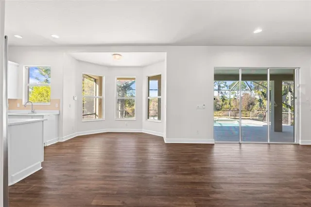 a view of an empty room with wooden floor and a large window