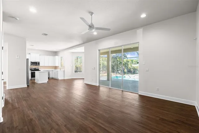 an empty room with windows and chandelier fan