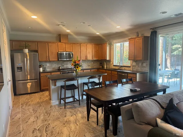 a kitchen with a refrigerator a stove a sink a dining table and chairs