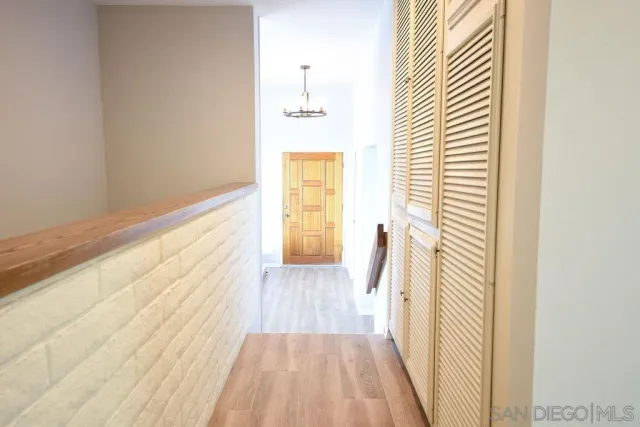 a view of a hallway with wooden floor and a bathroom