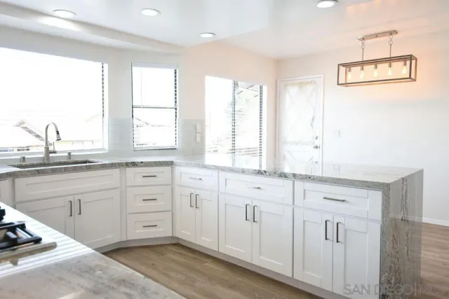 a kitchen with granite countertop white cabinets and white stainless steel appliances