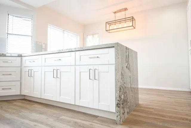 a view of a kitchen with white cabinets and wooden floor