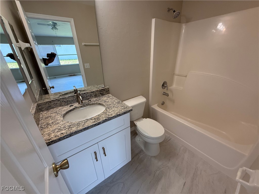 4547 21st Street Southwest Lehigh Acres, FL 33973 - Photo 11 of 12 a bathroom with a granite countertop sink toilet and shower