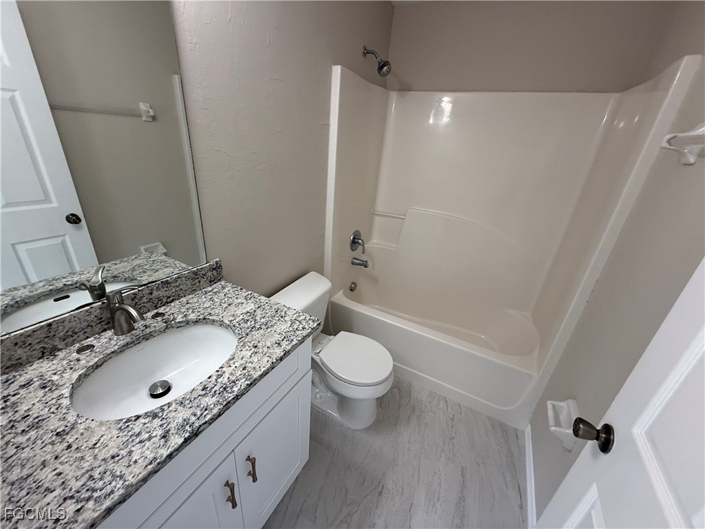 4547 21st Street Southwest Lehigh Acres, FL 33973 - Photo 8 of 12 a bathroom with a granite countertop sink toilet and shower
