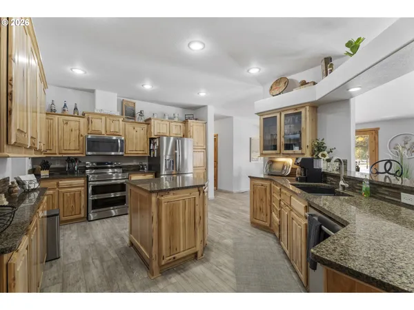 a kitchen with kitchen island granite countertop a stove top oven a sink dishwasher a dining table and chairs with wooden floor