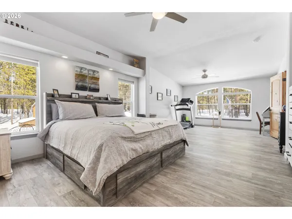 a spacious bedroom with a large bed a chandelier and windows