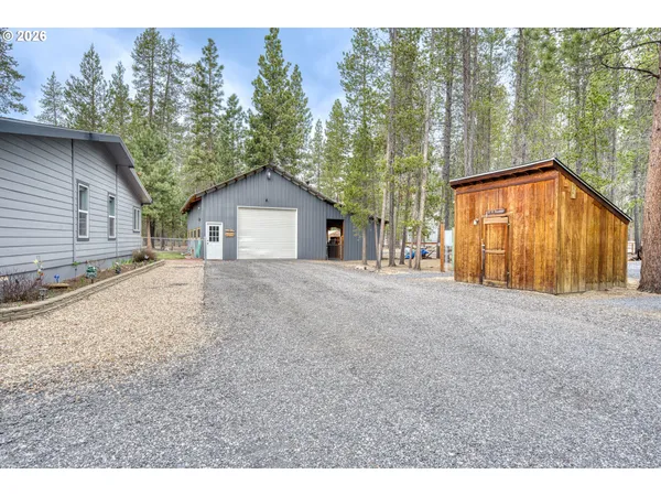 a view of house with backyard and trees in the background