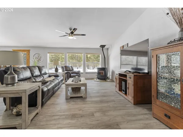 a living room with stainless steel appliances kitchen island granite countertop a stove a refrigerator a sink a dining table and chairs with wooden floor