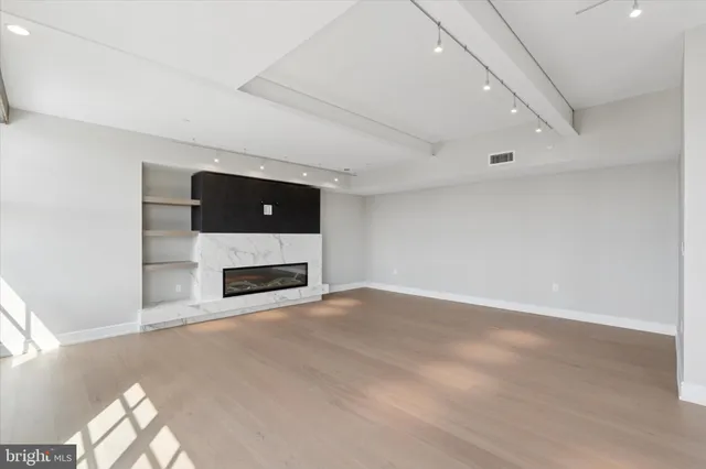 an empty room with wooden floor and windows