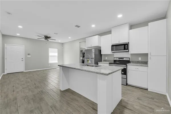 a kitchen with granite countertop a sink appliances cabinets and a counter top space