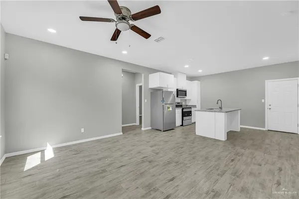 a view of kitchen with stainless steel appliances refrigerator stove and wooden floor