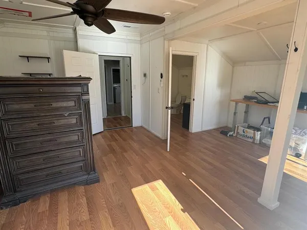a view of a hallway to a room with wooden floor and staircase