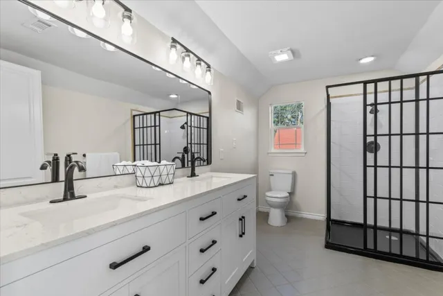 a bathroom with a double vanity sink toilet and a mirror