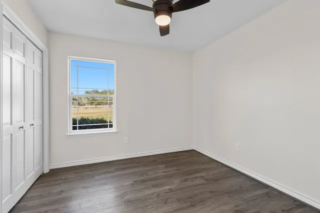 an empty room with wooden floor and windows