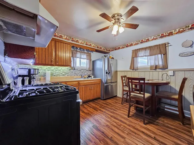 a kitchen with granite countertop a table chairs a sink dishwasher stove and cabinets with wooden floor