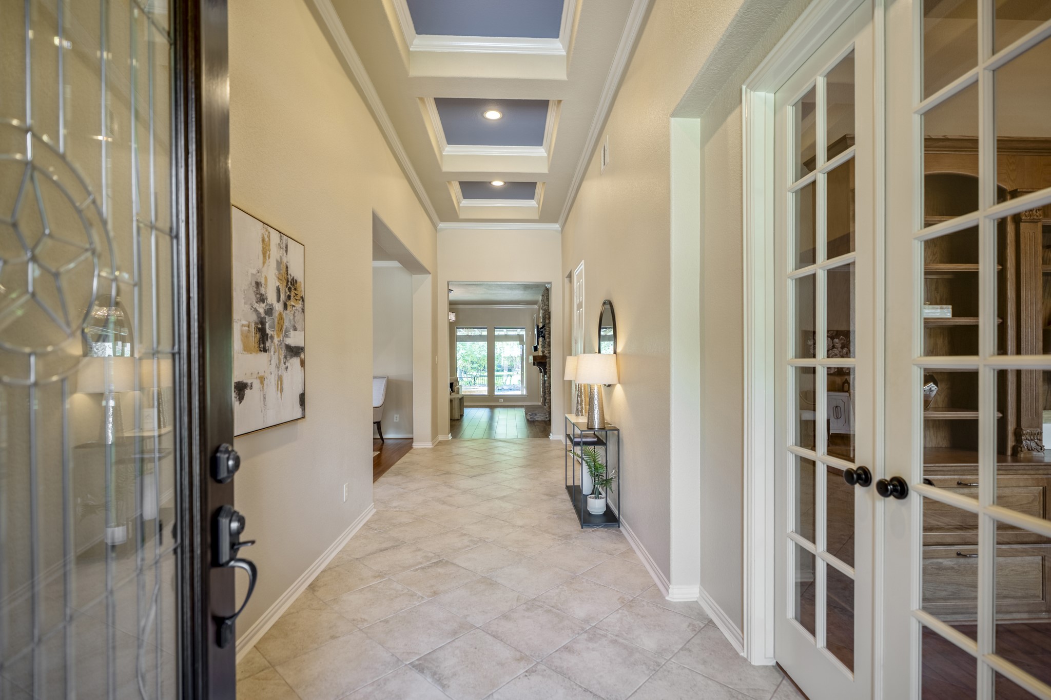 2407 Hendricks Lakes Drive Spring, TX 77388 - Photo 4 of 50 Stepping inside, the foyer introduces the home’s tailored feel with high ceilings and French doors opening to the office/study on the right. The path continues forward toward the main living areas, giving the first few steps inside a clear sense of flow before the home opens toward the kitchen, living room, and water-view backyard beyond.