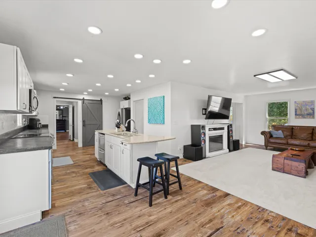 a large white kitchen with wooden floor and stainless steel appliances
