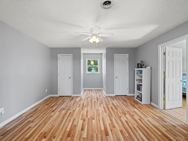 a view of a room with wooden floor closet and ceiling fan