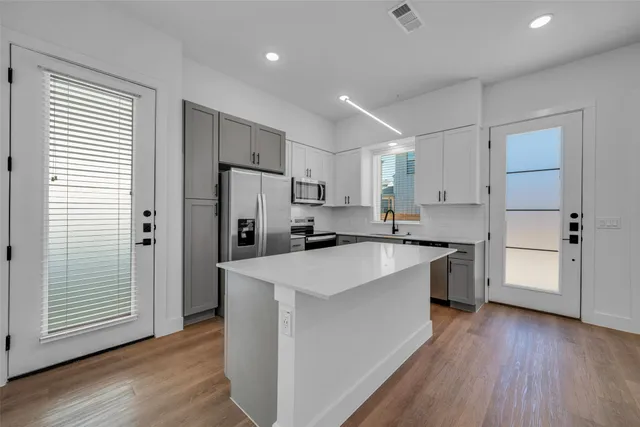 a kitchen with white cabinets appliances and wooden floor
