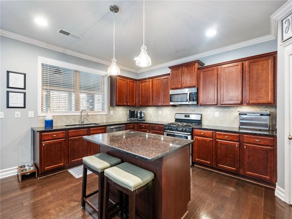 2939 Estate View Court Dacula, GA 30019 - Photo 18 of 73 a kitchen with stainless steel appliances granite countertop wooden cabinets a dining table and chairs